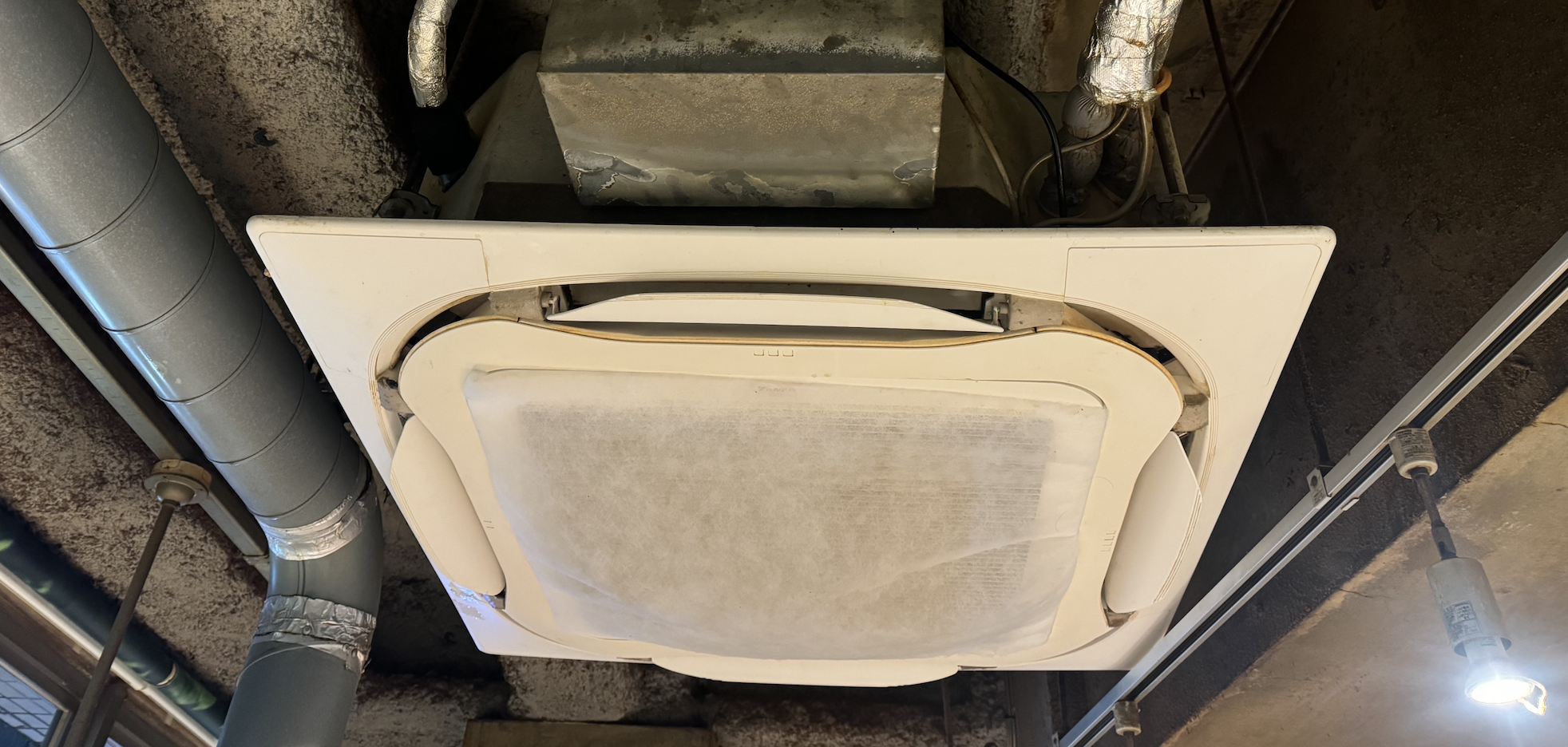 天井に設置されたダイキンの業務用エアコン(4方向カセットタイプ)。パネルを開けて点検している様子