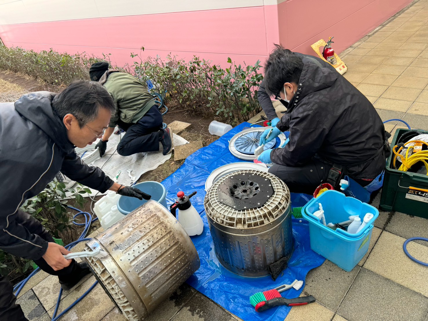 スタッフ2名で洗濯槽・パルセーターを分解して手作業で清掃している様子