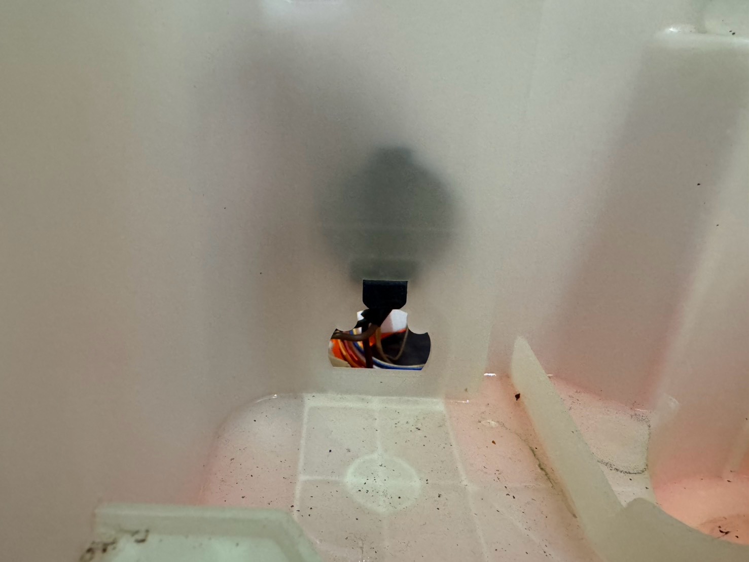 ヒートポンプ下部の水抜き穴（奥に配線が見える）