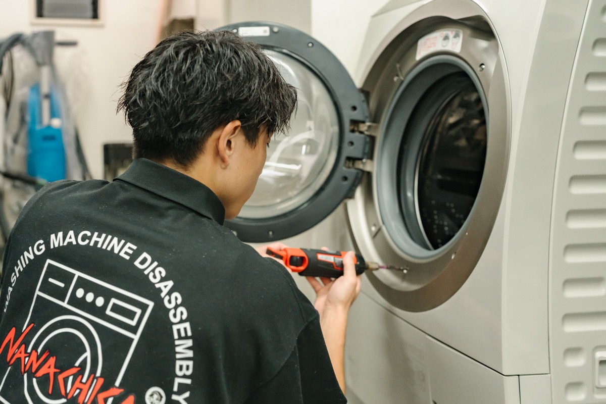 ドラム式洗濯機を分解するスタッフ
